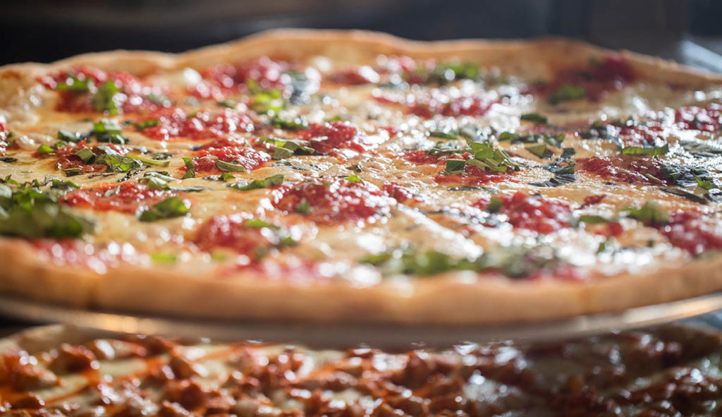 High quality pizza in slice shop featuring Grande Mozzarella cheese